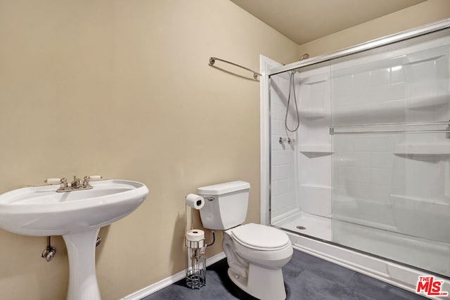 bathroom featuring sink, a shower with door, and toilet