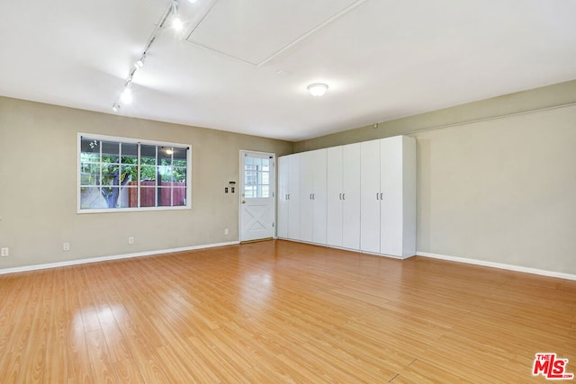 unfurnished bedroom with track lighting and light hardwood / wood-style flooring