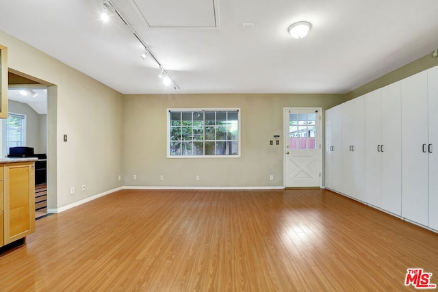 unfurnished living room featuring track lighting and light wood-type flooring