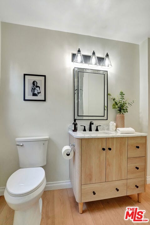 bathroom featuring wood-type flooring, toilet, and vanity