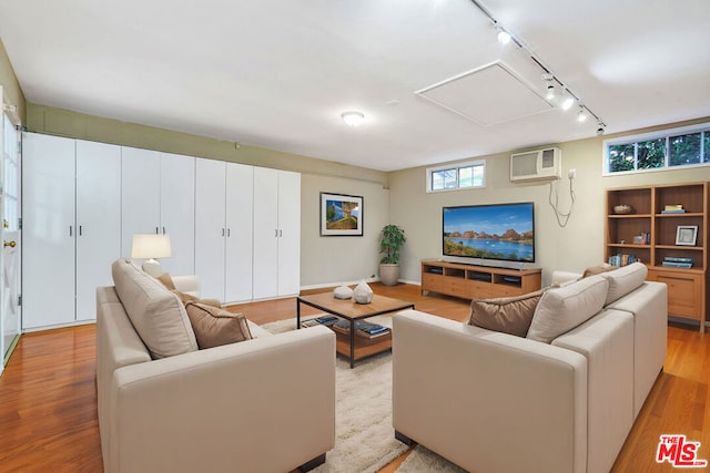 living room with track lighting, light hardwood / wood-style floors, and an AC wall unit