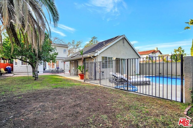 rear view of house with a fenced in pool, a patio, and solar panels