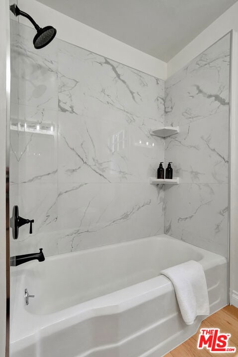 bathroom with tiled shower / bath and wood-type flooring