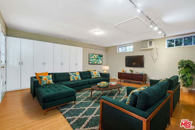 living room featuring a wall mounted air conditioner, track lighting, and light hardwood / wood-style floors