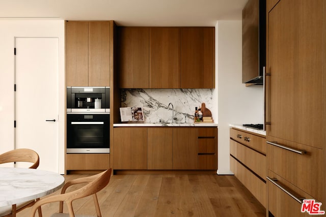 kitchen with sink, backsplash, light hardwood / wood-style flooring, and double wall oven