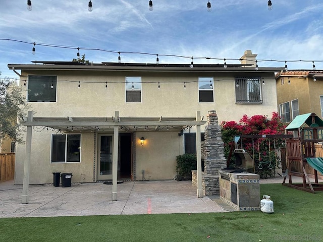 back of property with a patio area, a yard, and a playground