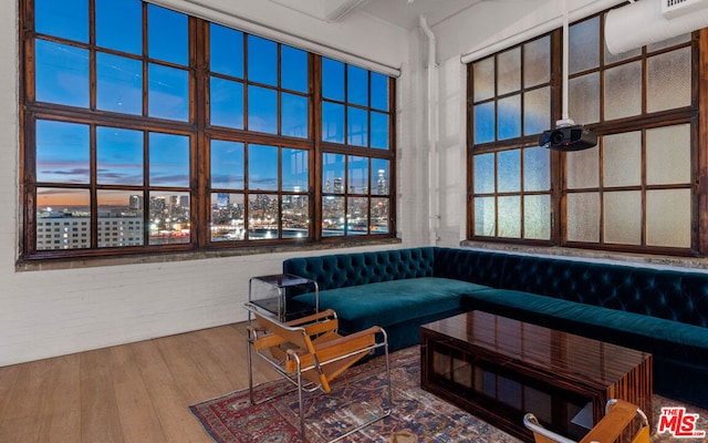 living room with breakfast area, brick wall, a high ceiling, and wood-type flooring