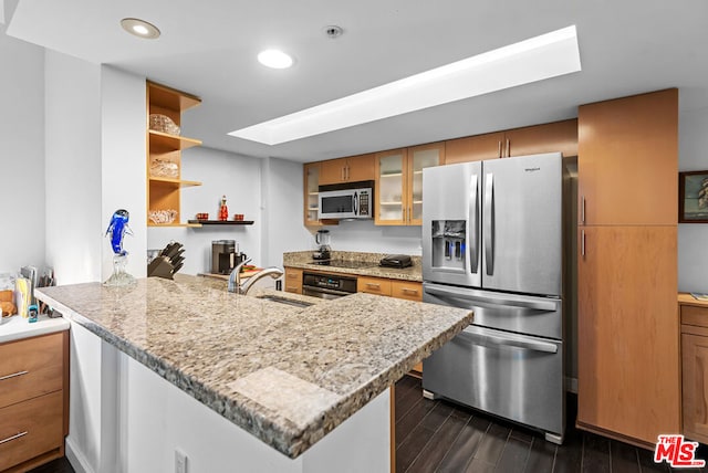 kitchen with light stone counters, sink, a skylight, and stainless steel appliances