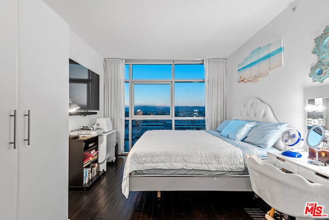 bedroom featuring a wall of windows and dark hardwood / wood-style flooring