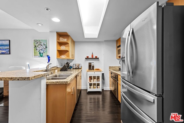 kitchen featuring appliances with stainless steel finishes, sink, kitchen peninsula, dark wood-type flooring, and a breakfast bar area