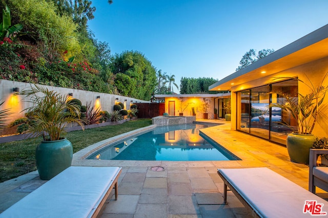 pool at dusk featuring a patio