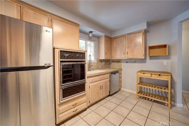 kitchen with light brown cabinetry, sink, tile countertops, and stainless steel appliances