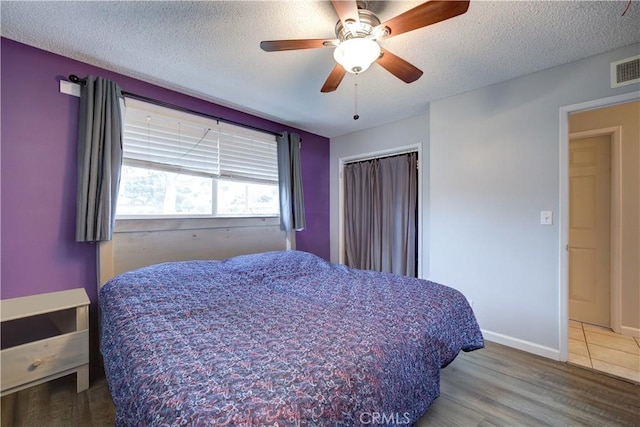 bedroom with ceiling fan, wood-type flooring, and a textured ceiling