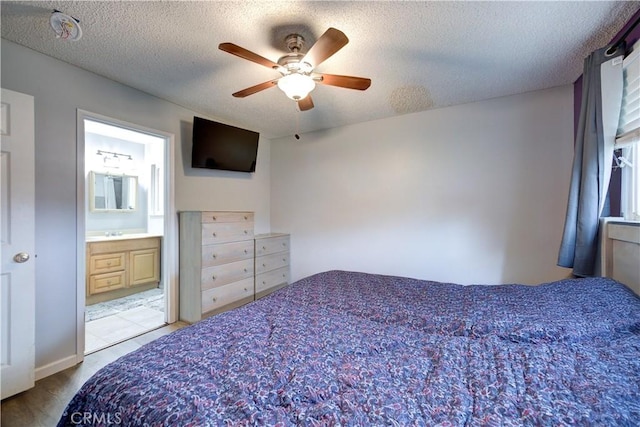 bedroom featuring ceiling fan, ensuite bath, and a textured ceiling