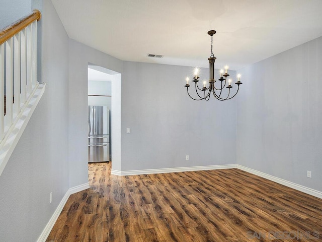 unfurnished room featuring a chandelier and dark hardwood / wood-style flooring