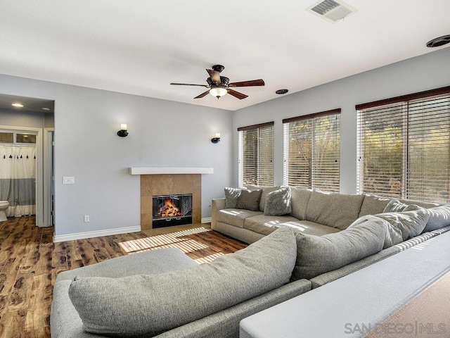 living room featuring hardwood / wood-style flooring, ceiling fan, and a tiled fireplace