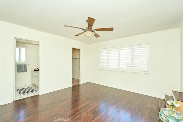 unfurnished bedroom featuring ceiling fan, dark wood-type flooring, ensuite bathroom, and a closet