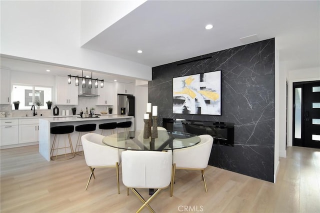 dining room with sink, tile walls, and light hardwood / wood-style flooring