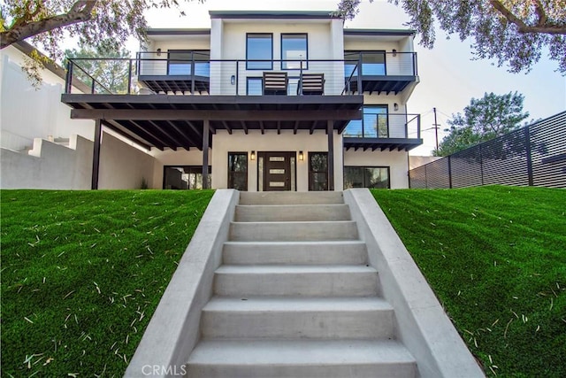 back of house with a balcony and a lawn