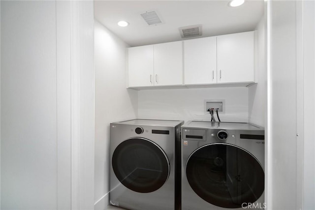 clothes washing area with cabinets and washer and clothes dryer