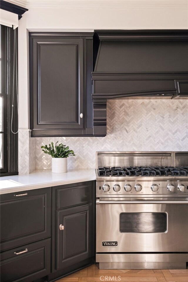 kitchen featuring wall chimney range hood, crown molding, decorative backsplash, and premium range