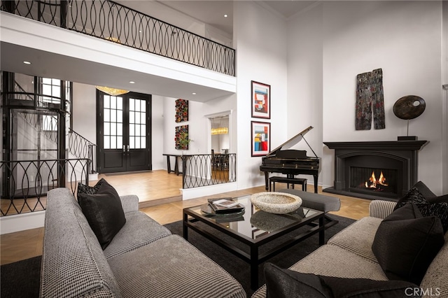 living area featuring stairway, a warm lit fireplace, and a towering ceiling
