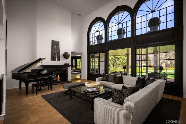 living area with a warm lit fireplace, recessed lighting, a high ceiling, crown molding, and baseboards