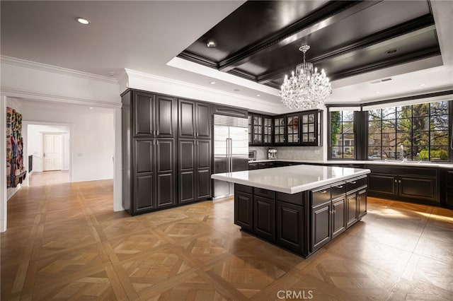 kitchen with stainless steel built in fridge, a notable chandelier, a center island, light countertops, and glass insert cabinets