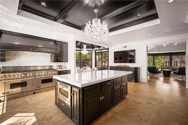 kitchen featuring crown molding, light countertops, appliances with stainless steel finishes, an inviting chandelier, and custom exhaust hood