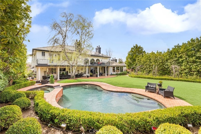 exterior space featuring a yard, a pool with connected hot tub, outdoor lounge area, and a patio