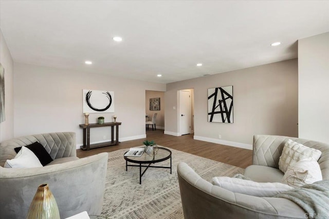 living area with baseboards, wood finished floors, and recessed lighting