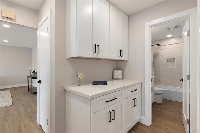 corridor with light wood-type flooring, baseboards, visible vents, and recessed lighting