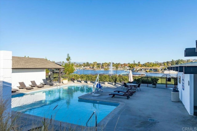 pool featuring a patio area, a water view, fence, and a gate