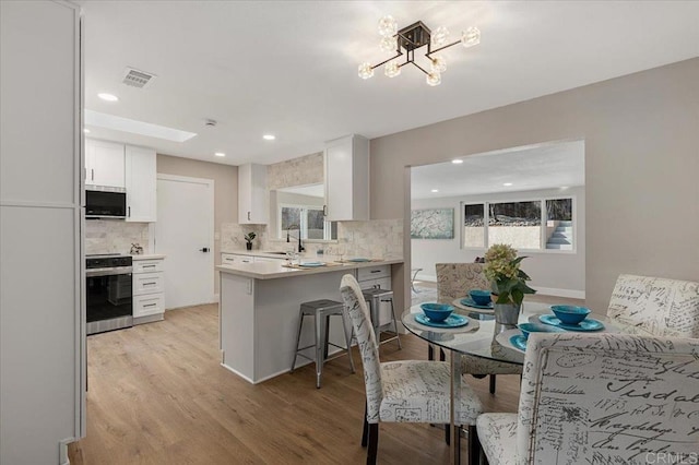 kitchen featuring a peninsula, visible vents, white cabinets, light countertops, and appliances with stainless steel finishes