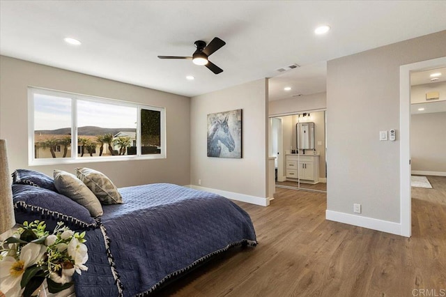 bedroom with wood finished floors, visible vents, and baseboards