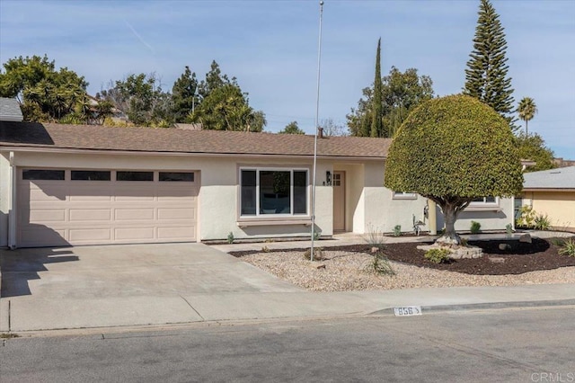 single story home with an attached garage, driveway, a shingled roof, and stucco siding