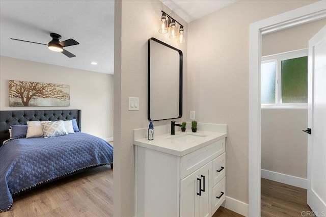 bedroom featuring baseboards, a sink, and light wood finished floors