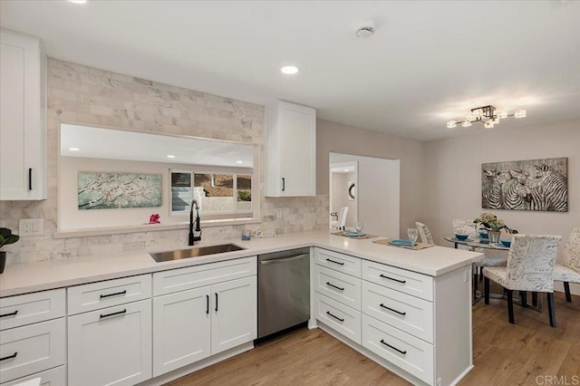 kitchen featuring light countertops, a sink, a peninsula, and stainless steel dishwasher