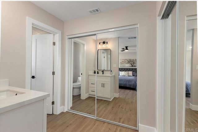 ensuite bathroom featuring toilet, visible vents, connected bathroom, and wood finished floors