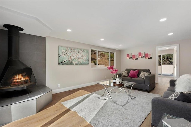 living area with recessed lighting, a wood stove, and wood finished floors