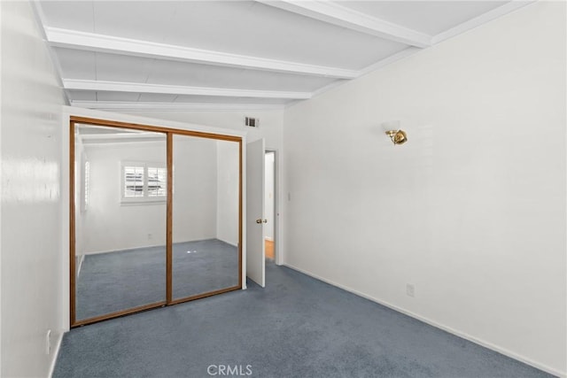 unfurnished bedroom featuring vaulted ceiling with beams, a closet, and carpet