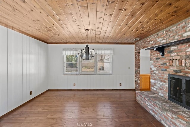 unfurnished dining area with a brick fireplace, hardwood / wood-style floors, wood ceiling, and an inviting chandelier