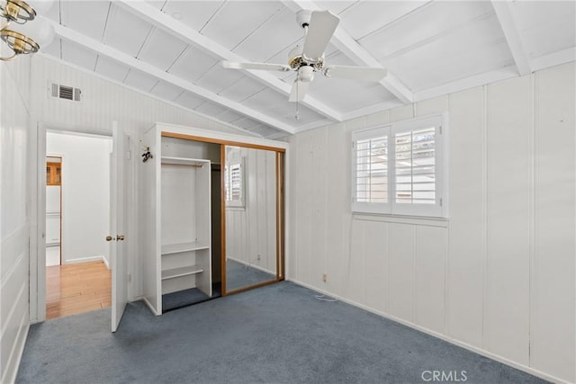 unfurnished bedroom featuring dark colored carpet, vaulted ceiling with beams, a closet, and ceiling fan