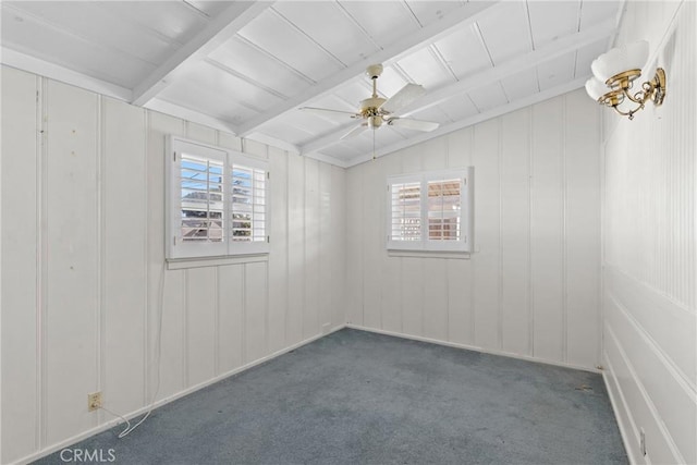 empty room featuring dark colored carpet, plenty of natural light, vaulted ceiling with beams, and ceiling fan