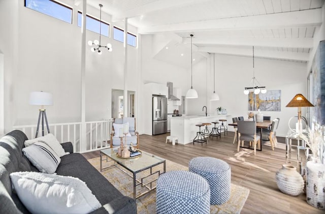 living room with sink, an inviting chandelier, high vaulted ceiling, wood-type flooring, and beamed ceiling