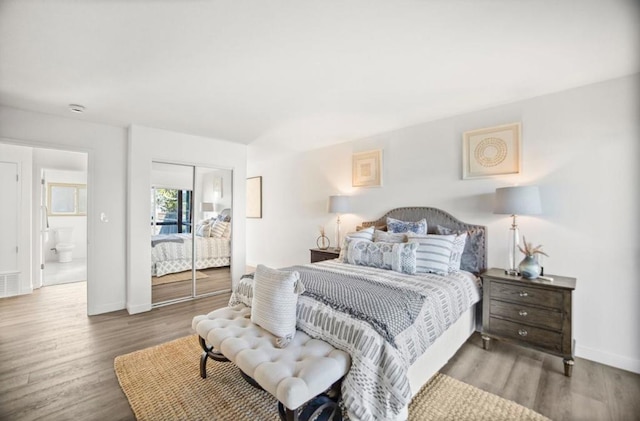 bedroom with hardwood / wood-style flooring and ensuite bath