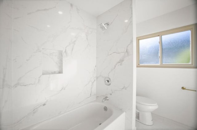 bathroom with tiled shower / bath combo and toilet