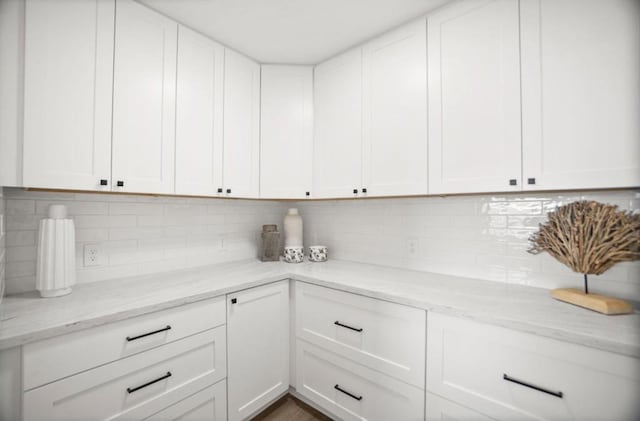 kitchen with light stone counters, decorative backsplash, and white cabinets