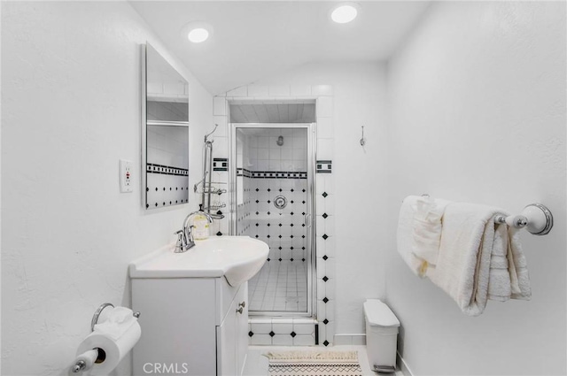 bathroom with tile patterned flooring, vaulted ceiling, walk in shower, and vanity