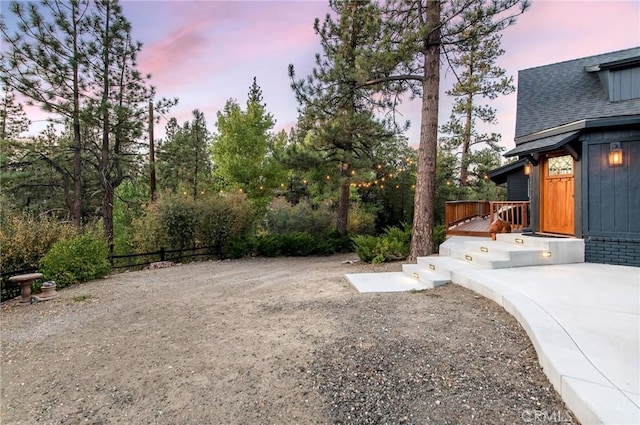 yard at dusk featuring a wooden deck